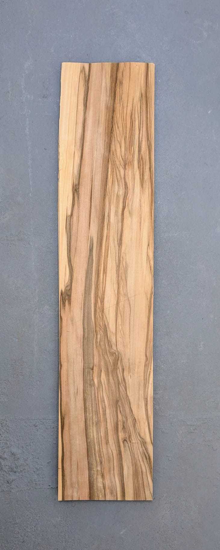 Los vel Red gum (satijnnoten) fineer 80x16 cm op grijze ondergrond, naturel en onbehandeld voor marqueterie of renovatieprojecten.